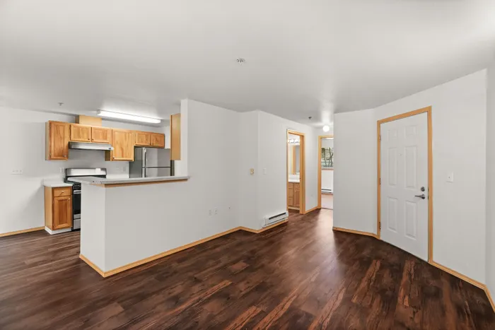 Charming apartment interior with rich wooden flooring, a cozy kitchen with modern cabinets, and a spacious open-plan design.