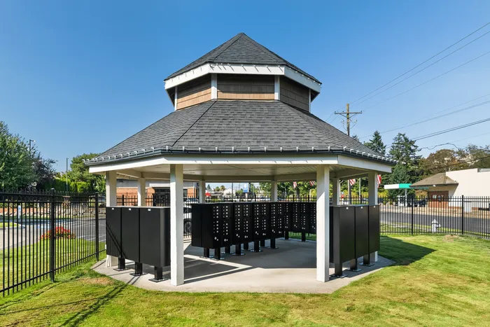 Charming outdoor mail pavilion with a sleek design, nestled in a beautifully landscaped community area.