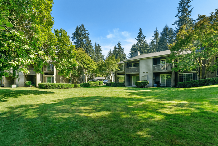 Charming apartment complex nestled in lush greenery with spacious balconies and serene surroundings.