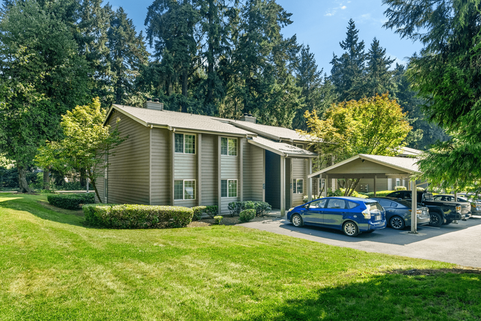 Charming apartment building nestled in lush greenery with covered parking and serene surroundings.
