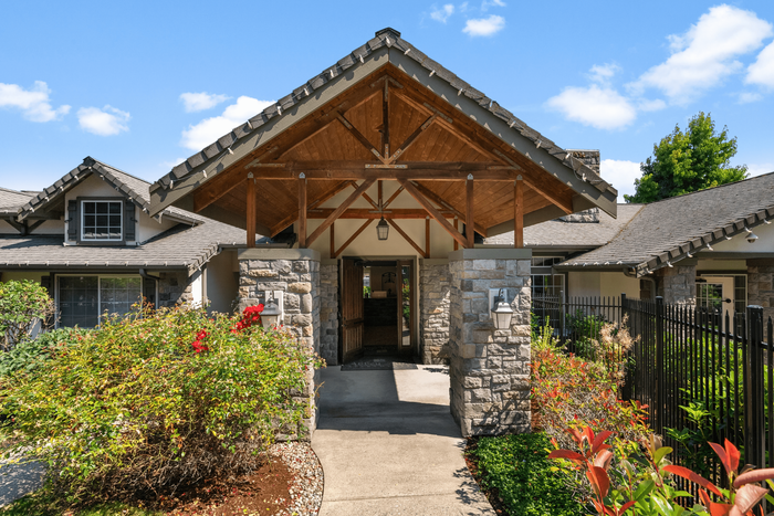 Charming stone-clad entrance of a modern home with lush landscaping and inviting architectural design.