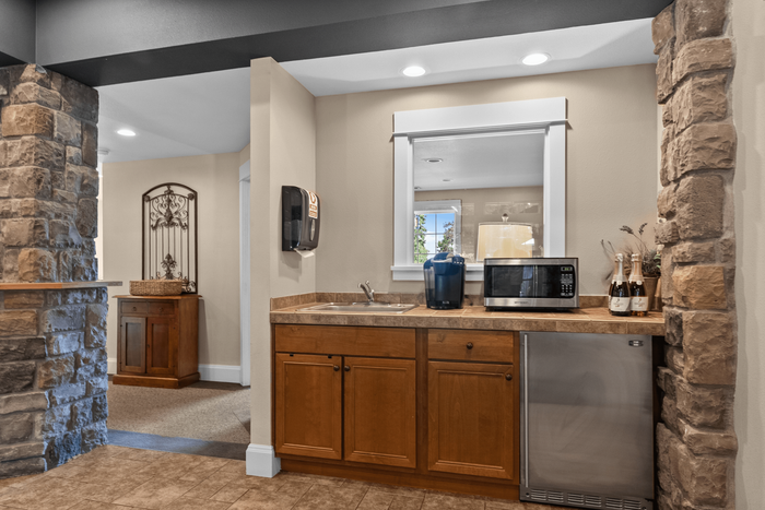Charming kitchenette with warm wooden cabinetry, stone accents, and modern appliances, creating a cozy and inviting atmosphere.