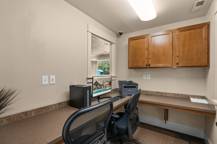 Cozy home office with modern desk setup, dual office chairs, wooden cabinets, and ample workspace lighting.
