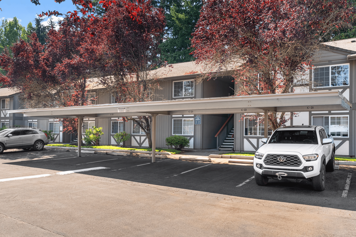Charming apartment complex with lush trees and convenient covered parking, perfect for comfortable living.