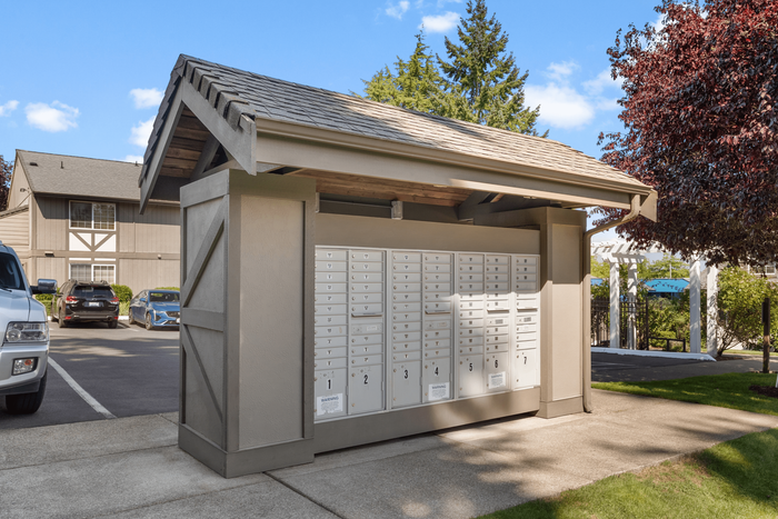 Charming community mailbox area with secure access, surrounded by lush greenery and a well-maintained parking lot.