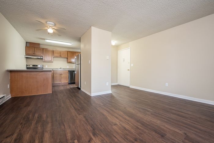 A modern kitchen featuring stainless steel appliances, wood cabinetry, and a speckled countertop with a built-in sink.
