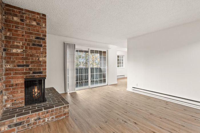 Charming living space featuring a cozy brick fireplace, elegant wood flooring, and large sliding glass doors for abundant natural light.
