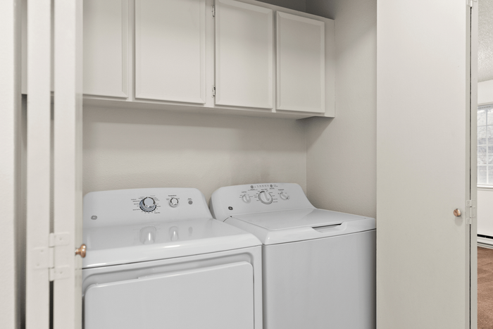 Charming laundry nook featuring modern washer and dryer beneath sleek white cabinets.