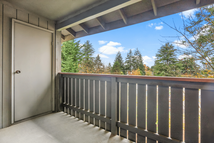 Private balcony with storage closet and view of trees