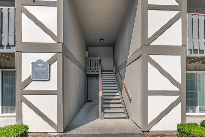 Inviting apartment entrance with modern architectural design and sleek staircase, surrounded by lush greenery.