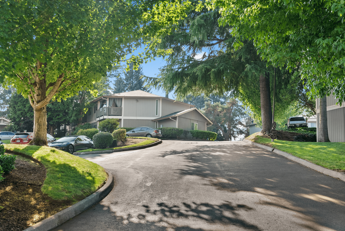 Charming residential area with lush greenery, showcasing a serene apartment complex under a bright blue sky.