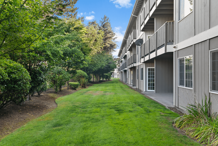 Charming garden-side view of a modern apartment complex featuring lush greenery and inviting balconies.