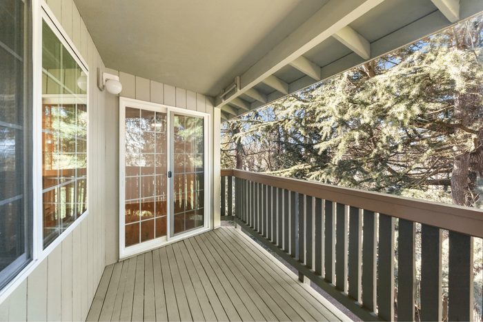 Charming balcony with elegant wooden railing and serene forest views, offering a peaceful retreat.