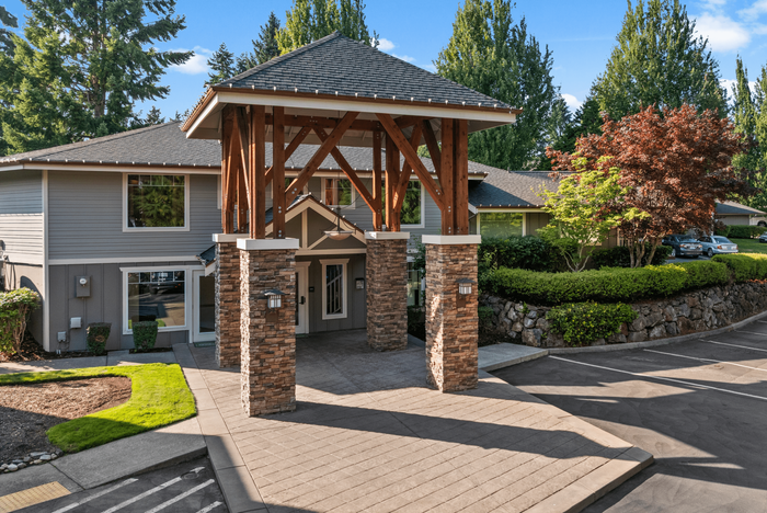 Charming apartment exterior with rustic wooden accents and well-manicured landscaping, nestled in a serene, natural setting.