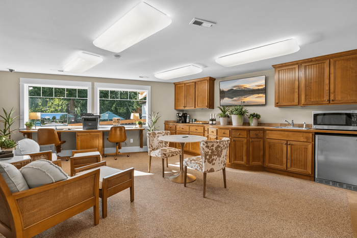 Charming home office space with natural light, featuring elegant wooden cabinetry, cozy seating, and lush greenery.