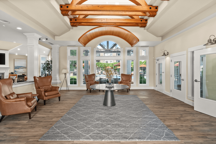 Elegant lobby with high wooden beams, large windows, and stylish leather seating, offering a spacious and welcoming atmosphere.