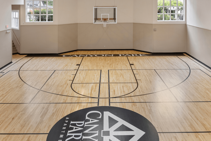 Luxurious indoor basketball court with polished wooden flooring and bright natural lighting at Canyon Park Apartments.