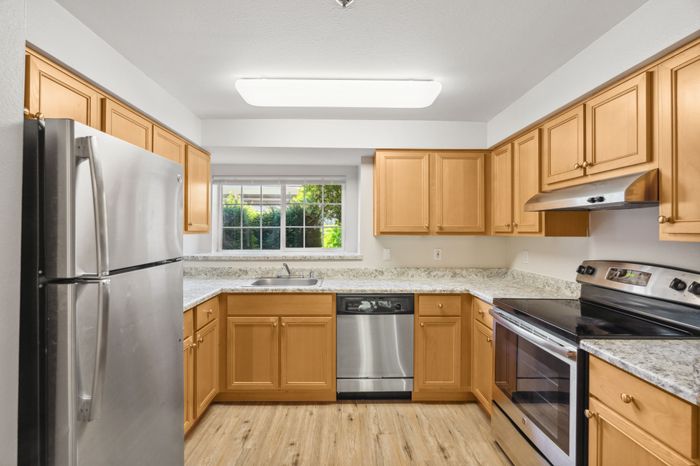 Modern kitchen with stainless steel appliances, granite countertops, and warm wooden cabinetry, offering a bright and inviting space.