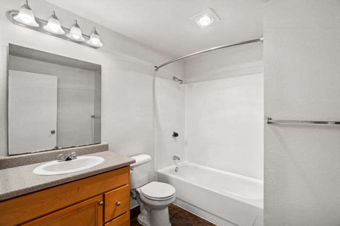 Bright and modern bathroom featuring elegant wooden cabinetry and a sleek shower-tub combination.