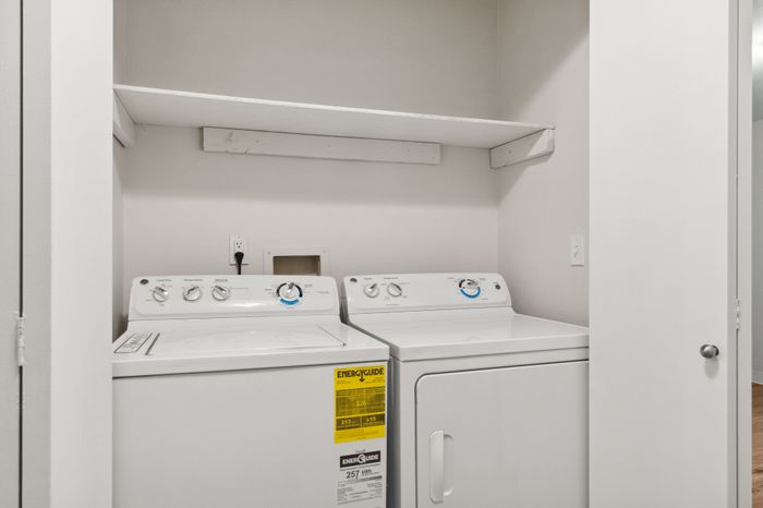 Bright and efficient laundry area featuring modern washer and dryer with convenient shelving.