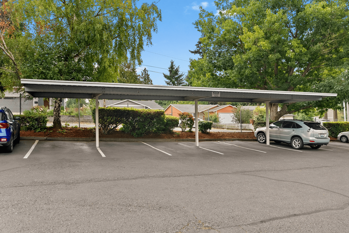 Covered parking area surrounded by lush greenery, offering convenient and secure parking options for residents.