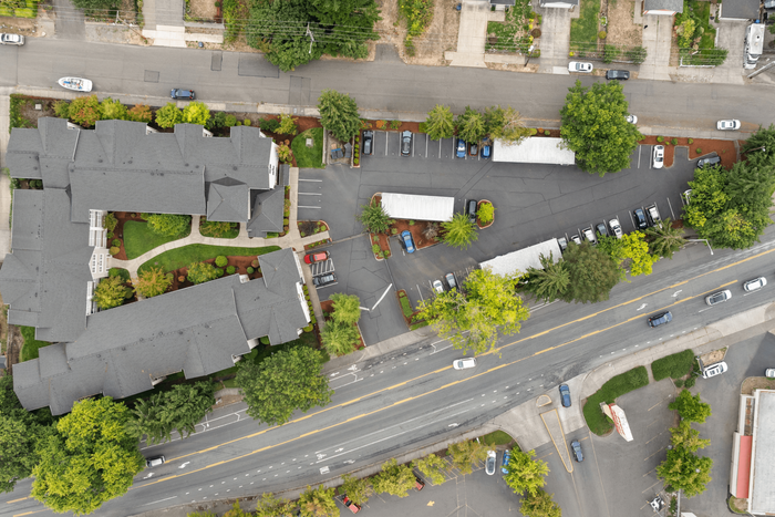 Stunning aerial view of a modern apartment complex surrounded by lush greenery, ample parking, and convenient street access.