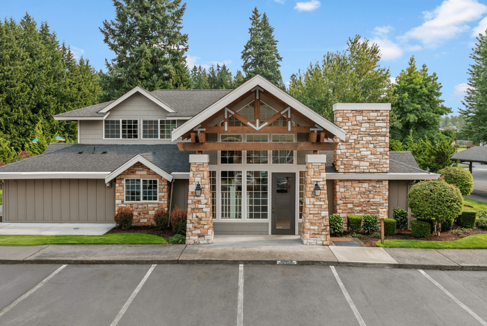 Charming brick-clad apartment complex nestled amidst lush greenery, featuring rustic wood accents and expansive windows.