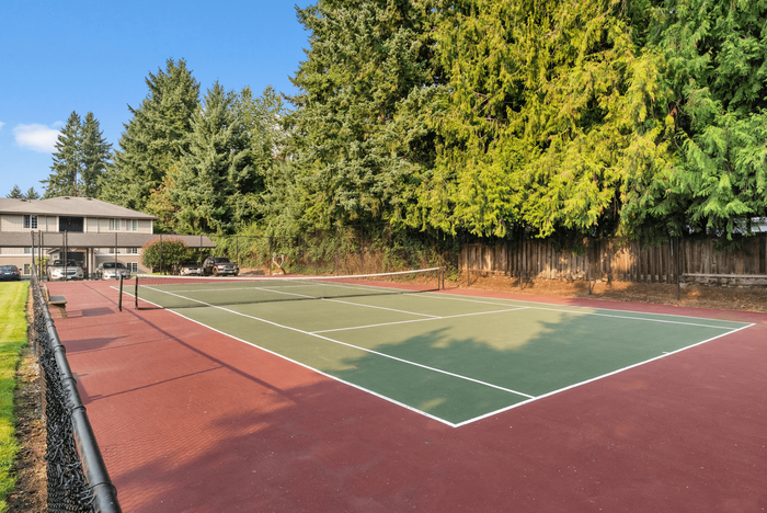 Inviting tennis court surrounded by lush greenery in a tranquil residential area, perfect for active living.