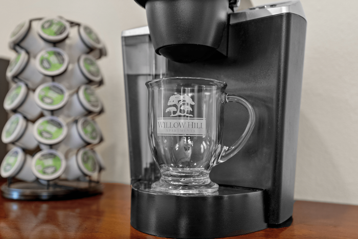 Modern coffee maker with a sleek glass mug and organized pod display at Willow Hill Apartments, offering a touch of luxury.