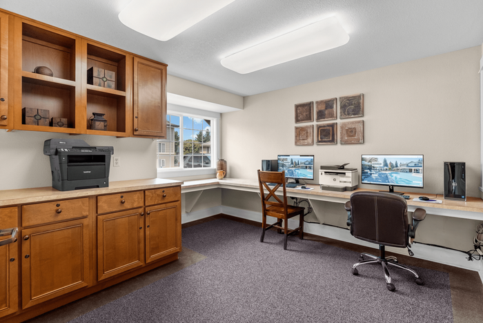 Chic home office space with elegant wooden cabinetry, dual computer setup, and large sunny window offering a bright and productive atmosphere.