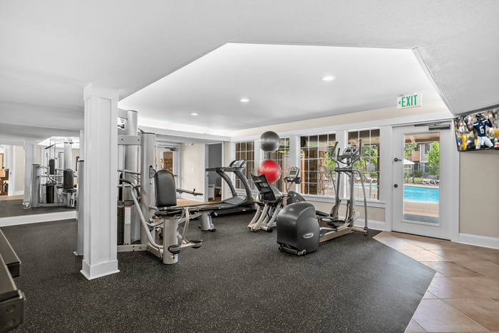 Modern fitness center featuring state-of-the-art gym equipment, large windows, and view of pool area.