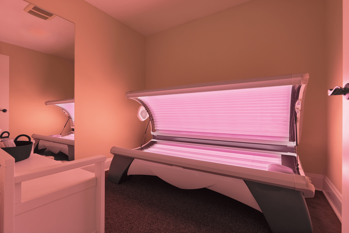 Inviting room with a modern tanning bed emitting a warm pink glow, perfect for relaxation and a sun-kissed look.