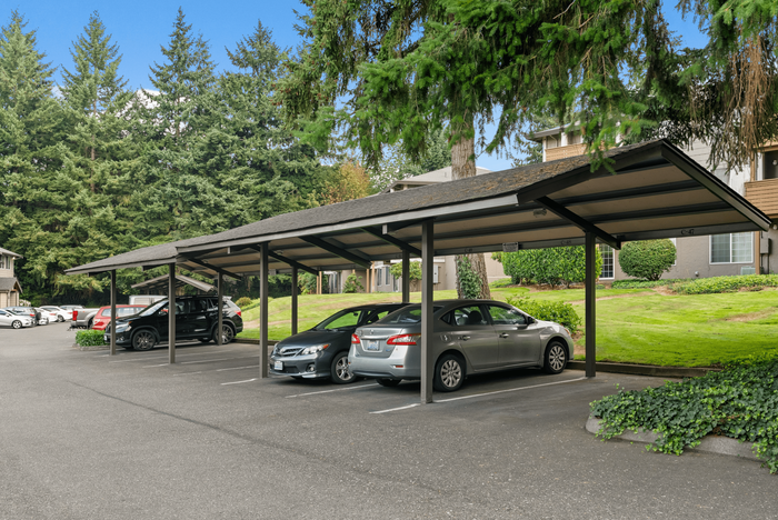 Inviting apartment complex featuring well-maintained covered parking surrounded by lush greenery and tall trees.