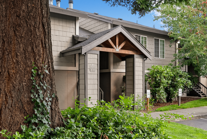 Charming apartment exterior with a modern entrance, lush greenery, and inviting architectural details.