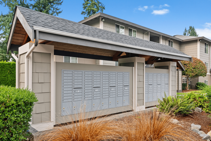 Charming residential mail center with convenient, neatly arranged mailboxes under a stylish covered structure, surrounded by lush greenery.