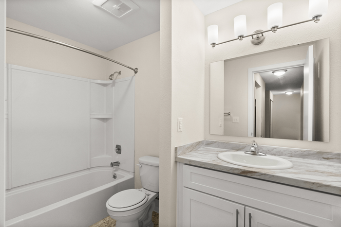 Modern bathroom design featuring a sleek vanity with marble countertop and a spacious bathtub, complemented by elegant lighting.