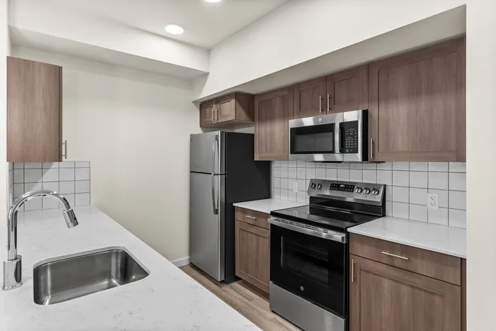 Contemporary kitchen design with sleek stainless steel appliances, chic wooden cabinetry, and elegant marble countertops.