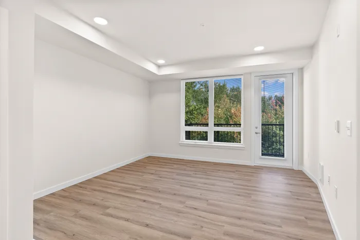 Bright and airy living room with large windows showcasing scenic views, featuring elegant hardwood floors and recessed lighting.