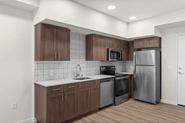 Modern kitchen with sleek stainless steel appliances, elegant wood cabinetry, and contemporary tile backsplash, offering a stylish and functional space.