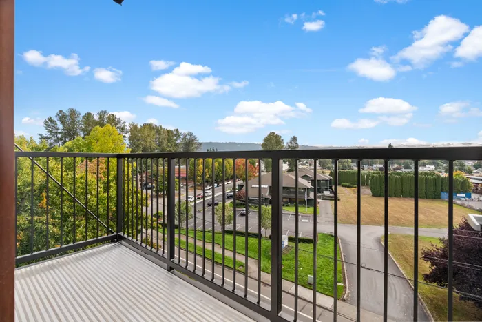 Charming balcony view showcasing scenic neighborhood, lush trees, and clear blue skies.