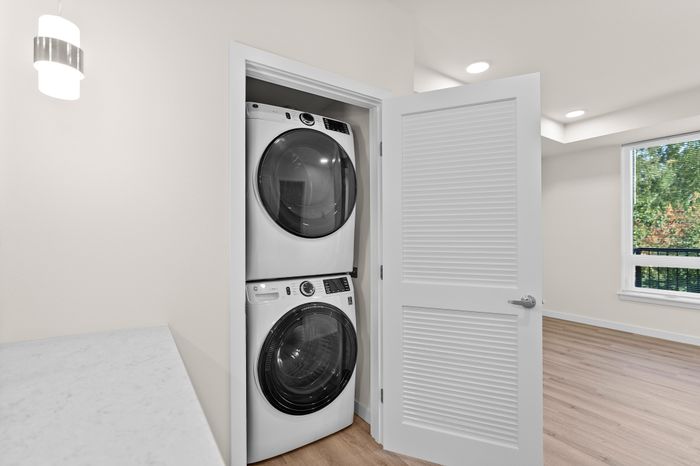 Bright open laundry area with modern stacked washer and dryer in a sleek apartment setting.