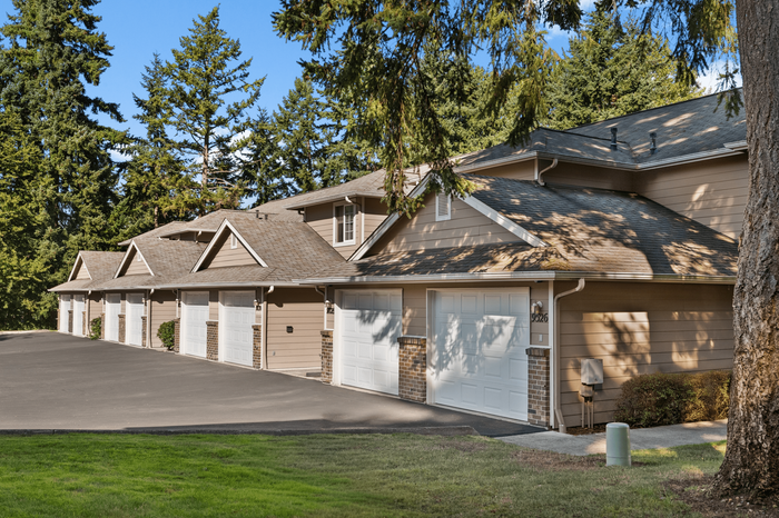 Charming townhouse complex with garages nestled among lush greenery, offering tranquil living in a serene environment.