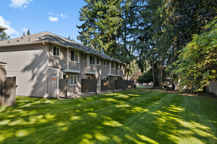 Charming townhouse nestled in a serene woodland setting with a lush green lawn, perfect for nature lovers seeking tranquil living.