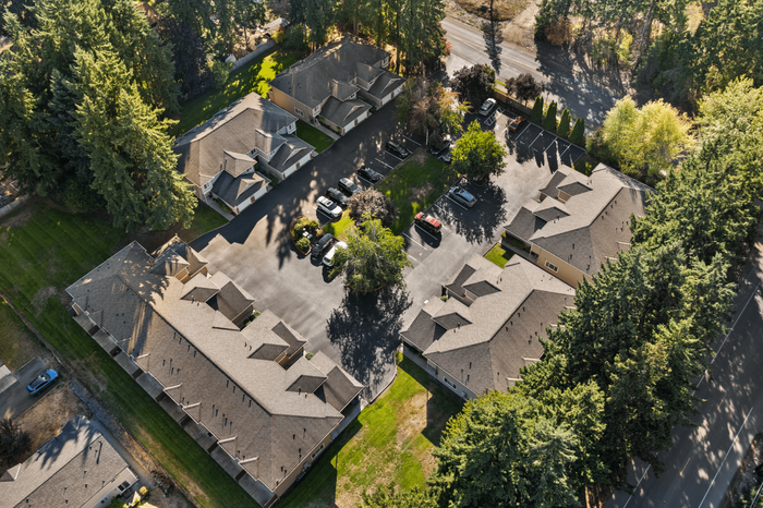 Beautiful aerial view of a serene apartment complex nestled among lush trees, featuring well-maintained roads and ample parking space, perfect for modern living.