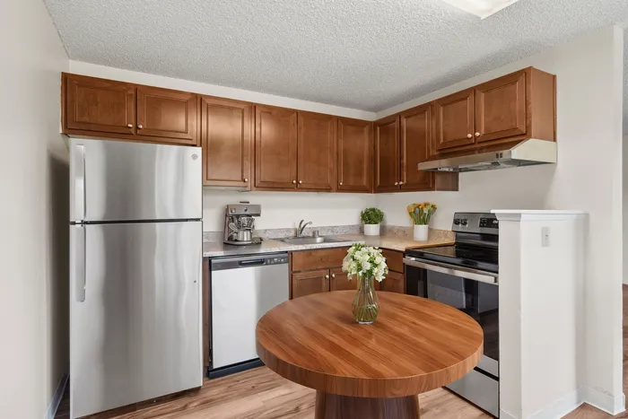 Modern kitchen featuring elegant wood cabinetry, a sleek stainless steel fridge, and a cozy round dining table with fresh flowers.