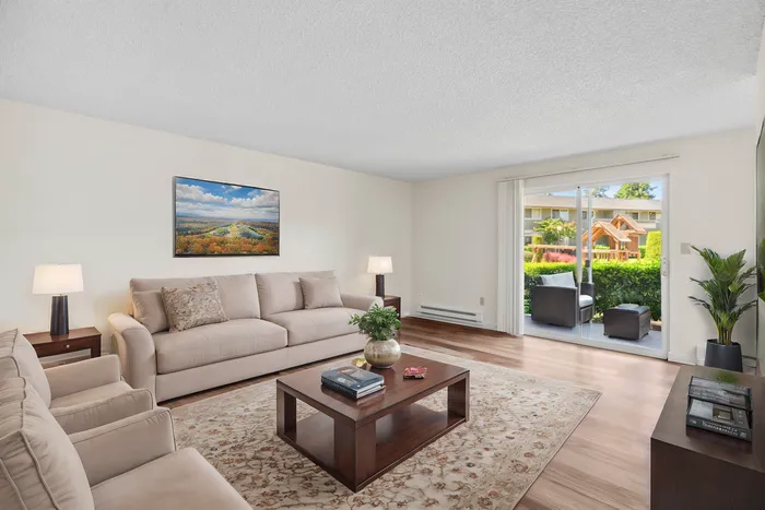 Bright and inviting living room with plush beige sofas, stylish coffee table, and a stunning view through sliding glass doors to a lush garden.