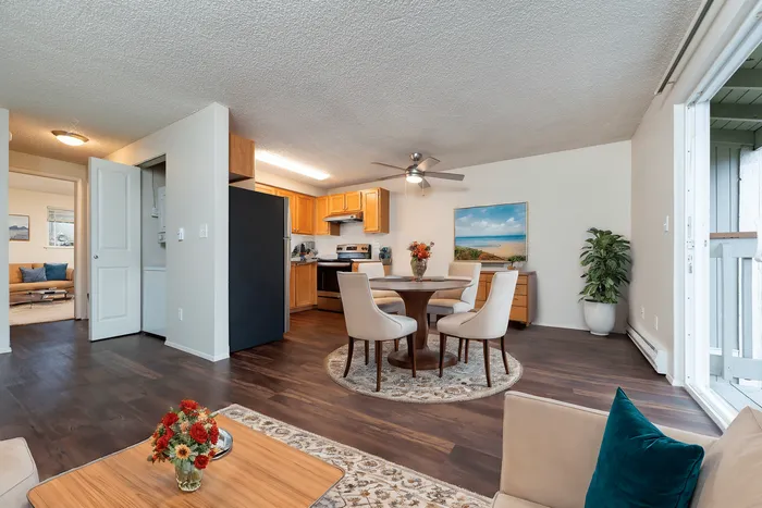 Inviting open-concept living space with elegant dining area, modern kitchen, and cozy seating, enhanced by rich wood flooring and vibrant decor.