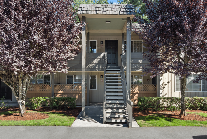 Charming apartment exterior with inviting entrance, lush landscaping, and serene atmosphere.