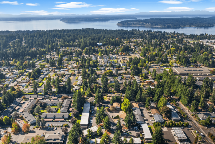 Breathtaking aerial view of a vibrant coastal community nestled among lush greenery, with scenic water and mountain vistas.