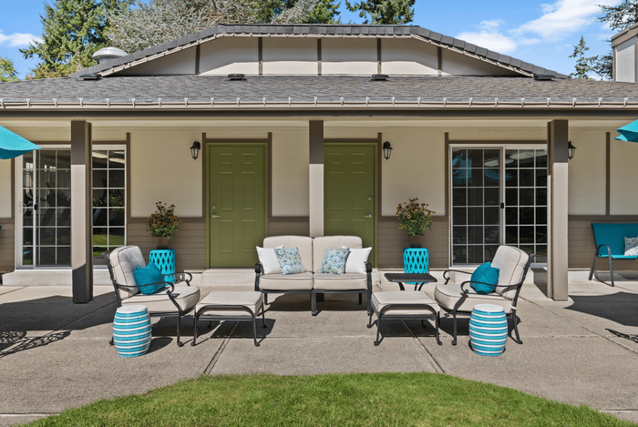 Charming outdoor patio with stylish seating and vibrant decor, featuring cozy cushions and lush greenery.
